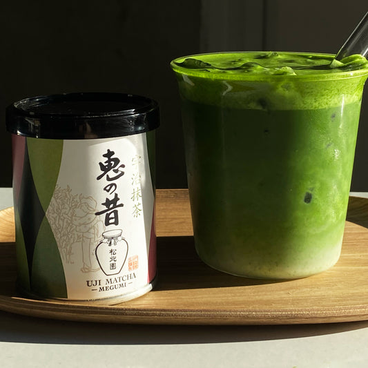 Megumi matcha tin next to a matcha latte made with Megumi.