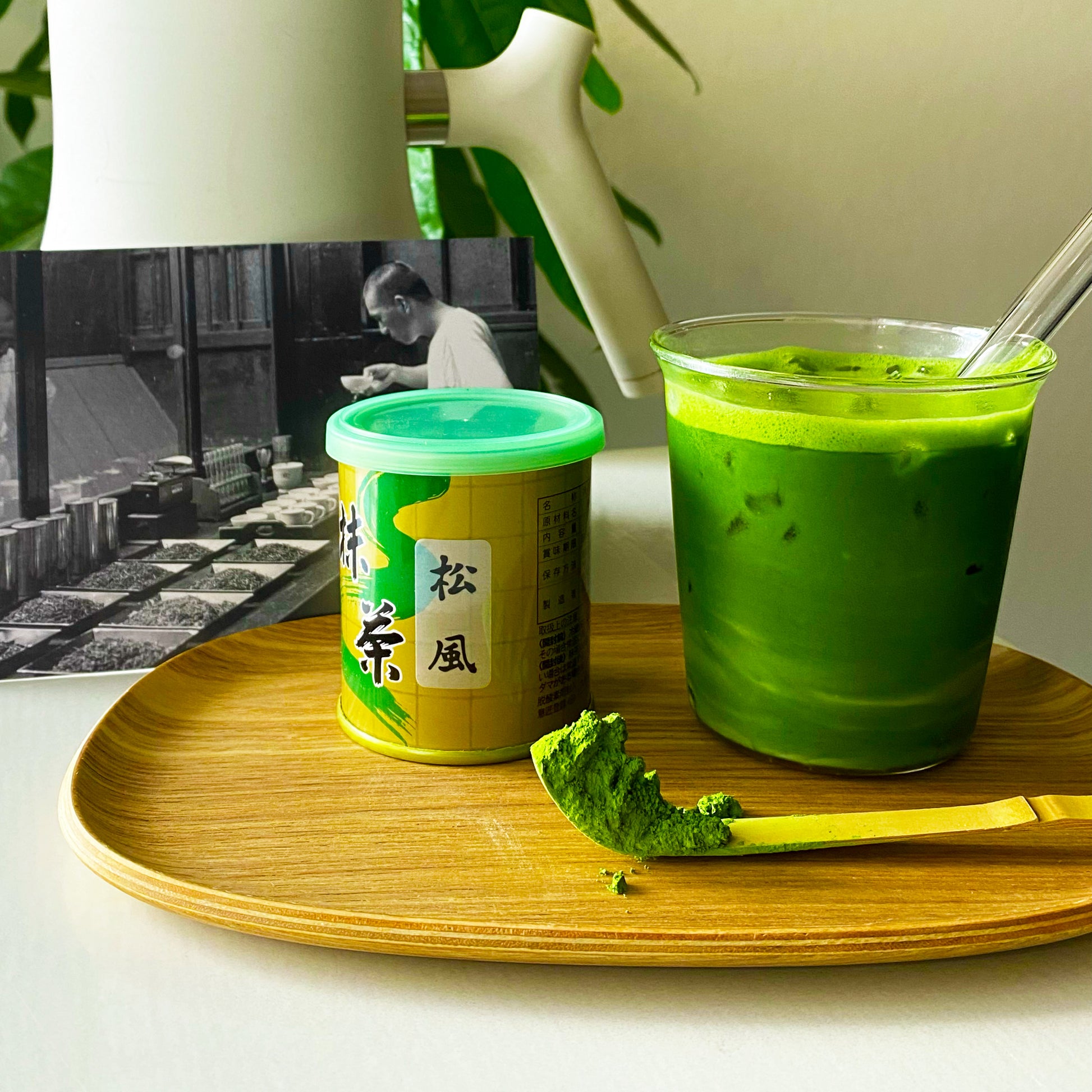 A 30 gram Matsukaze matcha can sitting next to a matcha latte and matsukaze matcha powder.