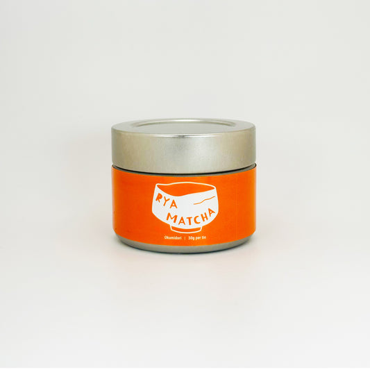 Rya Matcha tin with an orange label on a silver can with a silver lid. It is an Okumidori variety in a 30 gram tin.