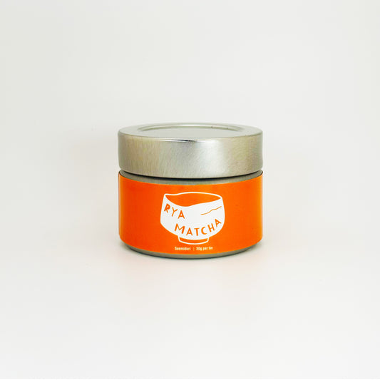 Orange container with silver lid featuring 'Rya Matcha' branding on a white background. Its the Saemidori varietal in a 30 gram tin.