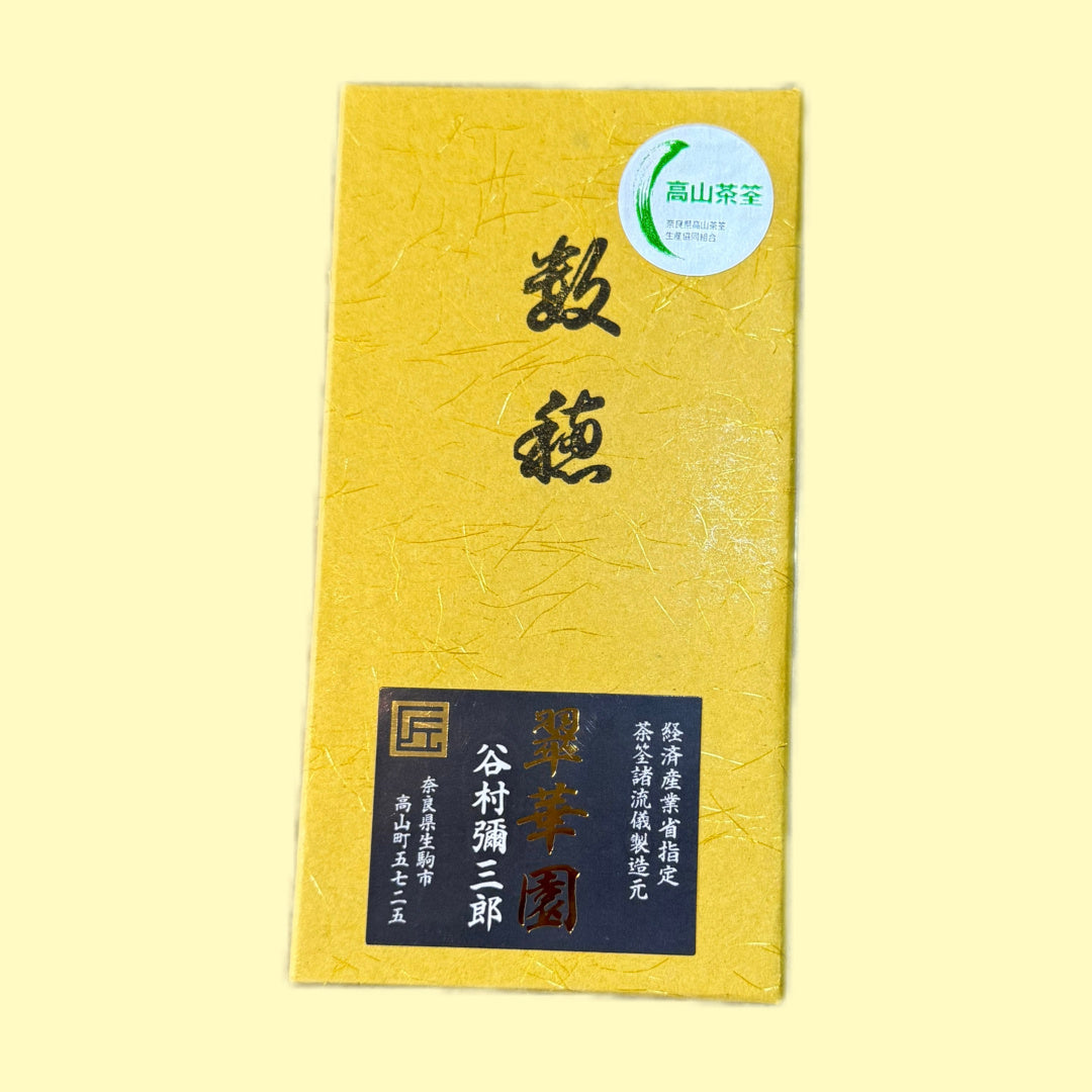 Suikaen Takayamachasen - Yellow box and black string Japanese Chasen. This image shows the cover of the box of the Chasen.